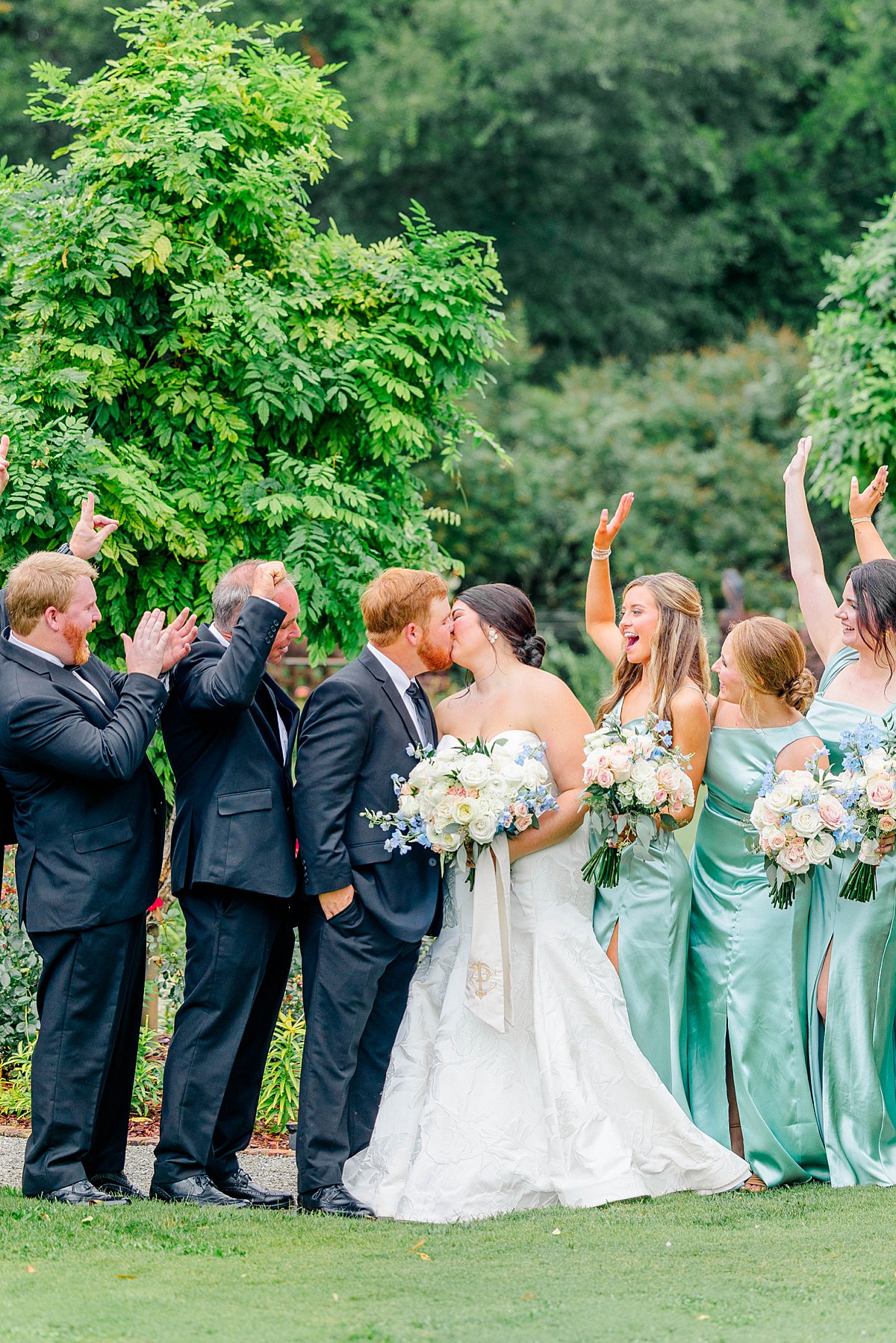 bridal party cheering as bride and groom share a kiss