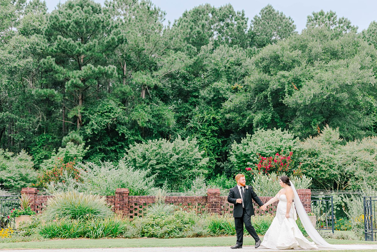 bride and groom holding hands as they walk through the gardens at britton manor wedding venue