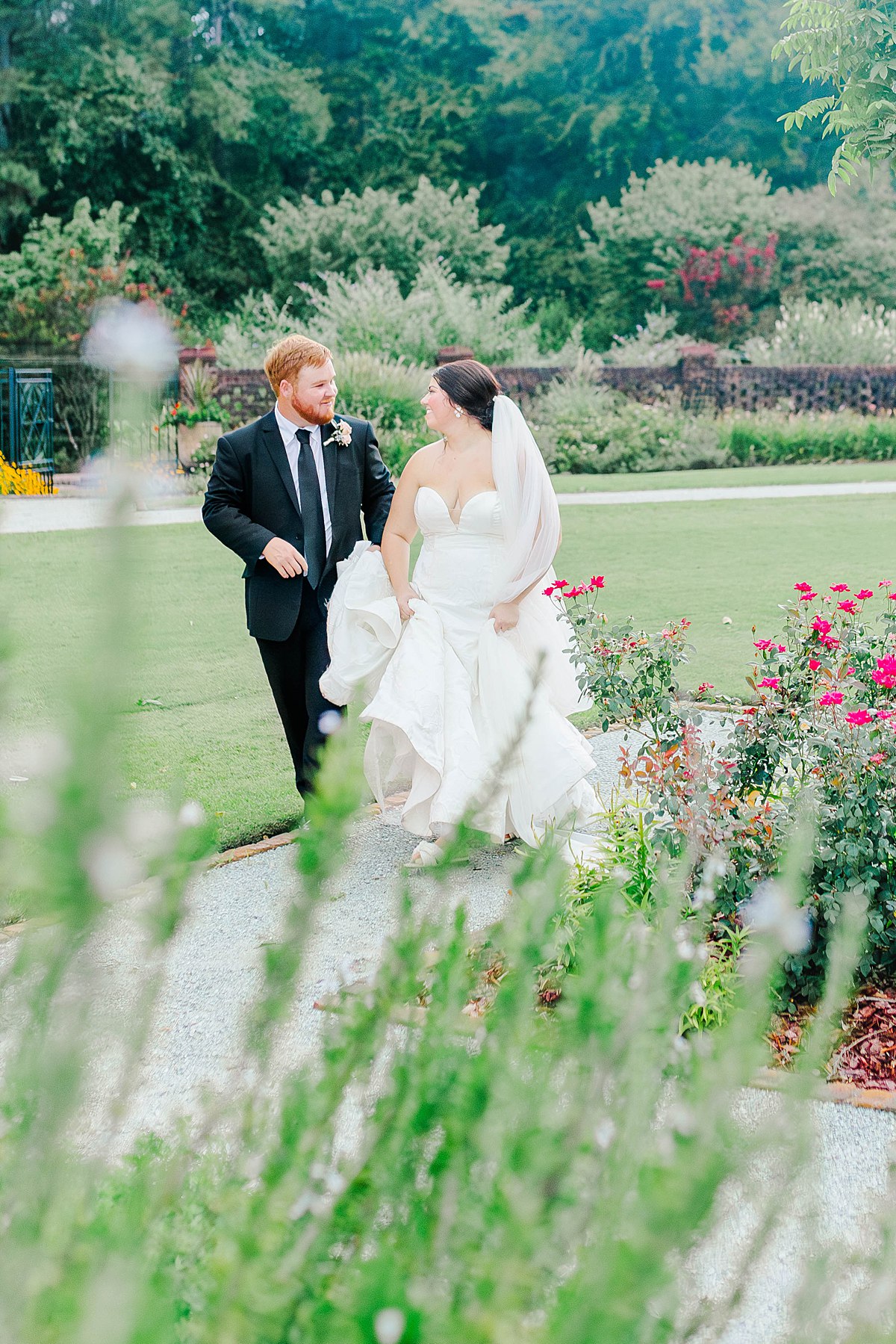 bride and groom walking through the gardens at britton manor wedding venue