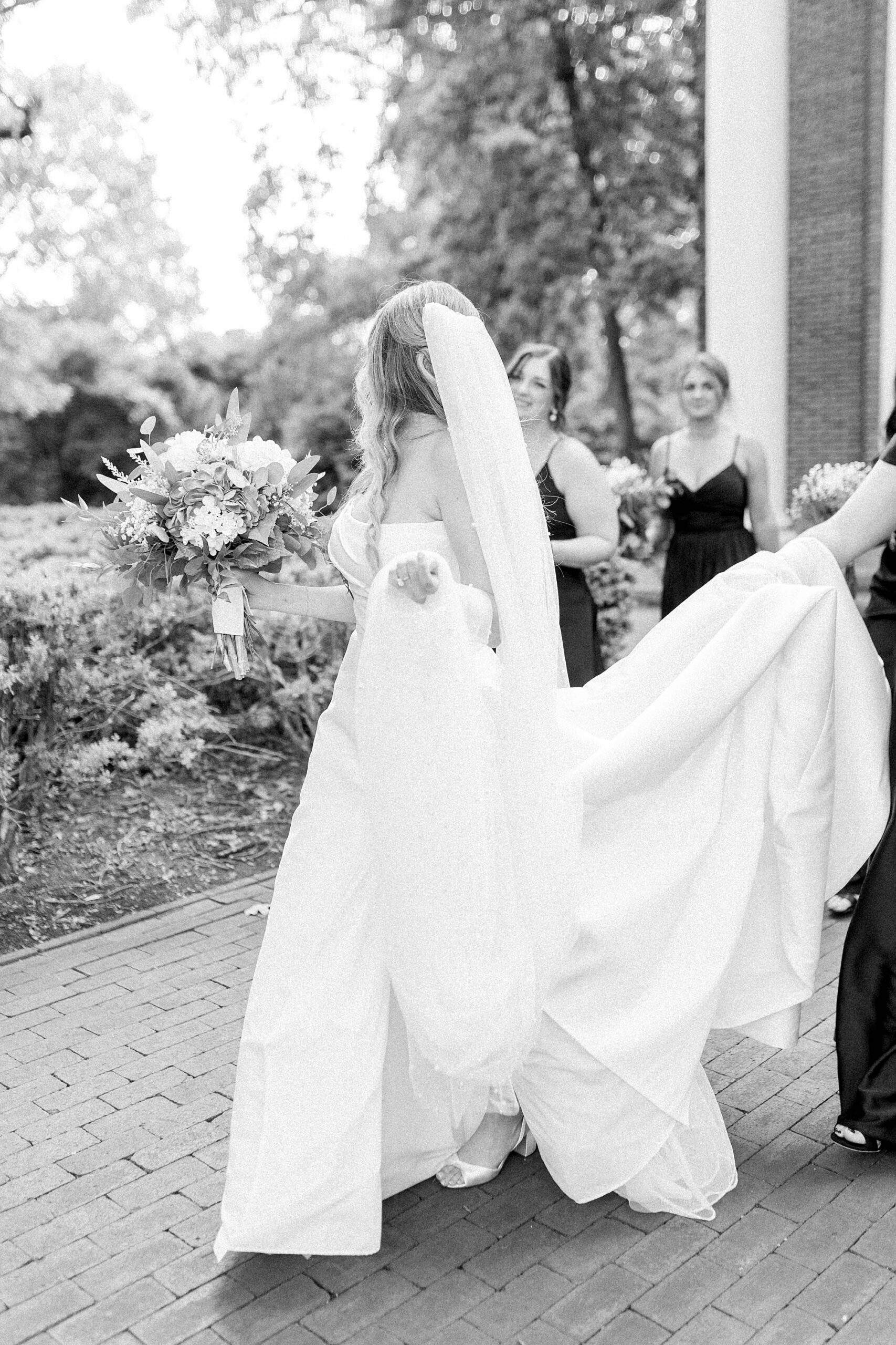 Bride walking with bridesmaids at wedding on Meredith College campus